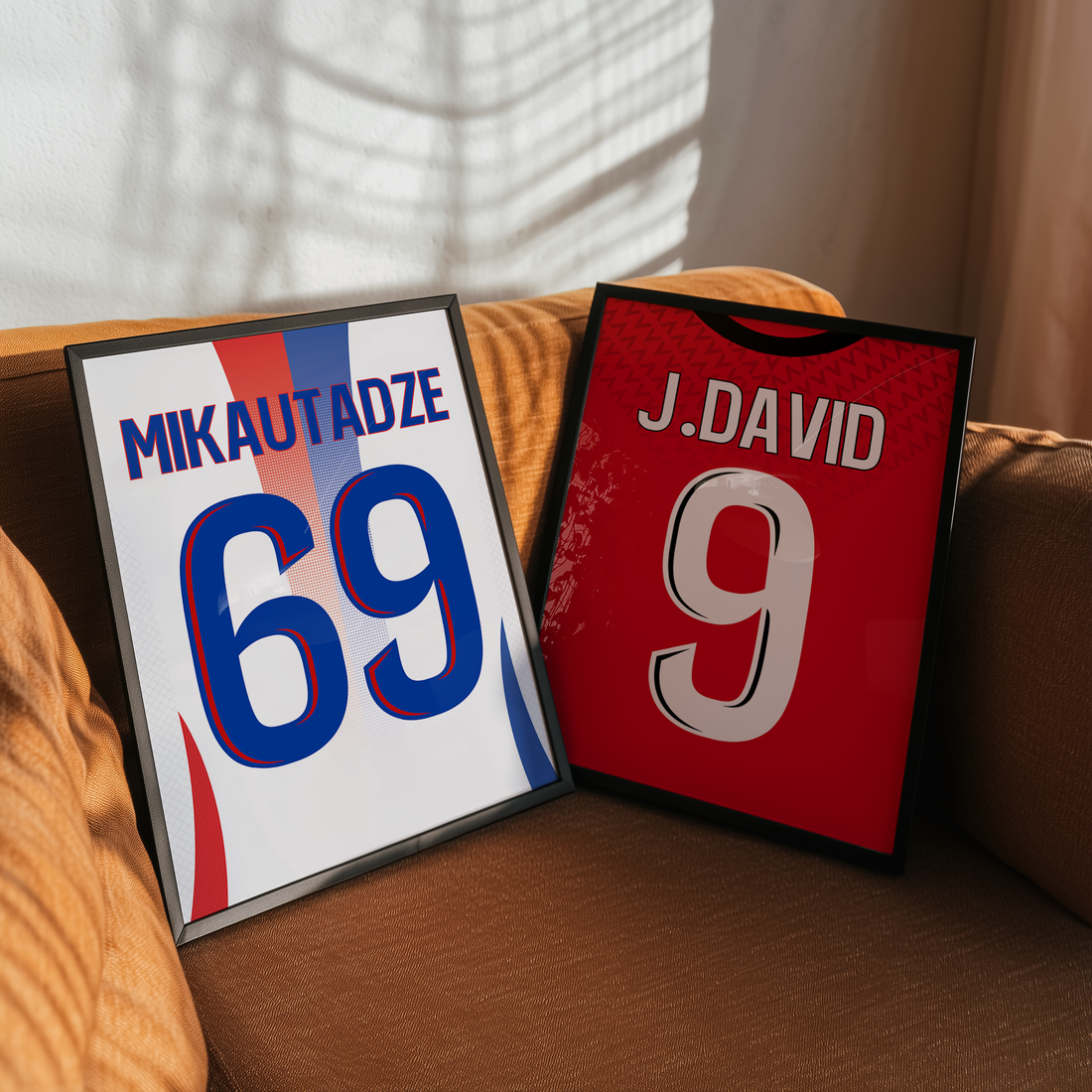 Deux cadres personnalisés de maillots de football posés sur un canapé, représentant Mikautadze pour Lyon et Jonathan David pour Lille